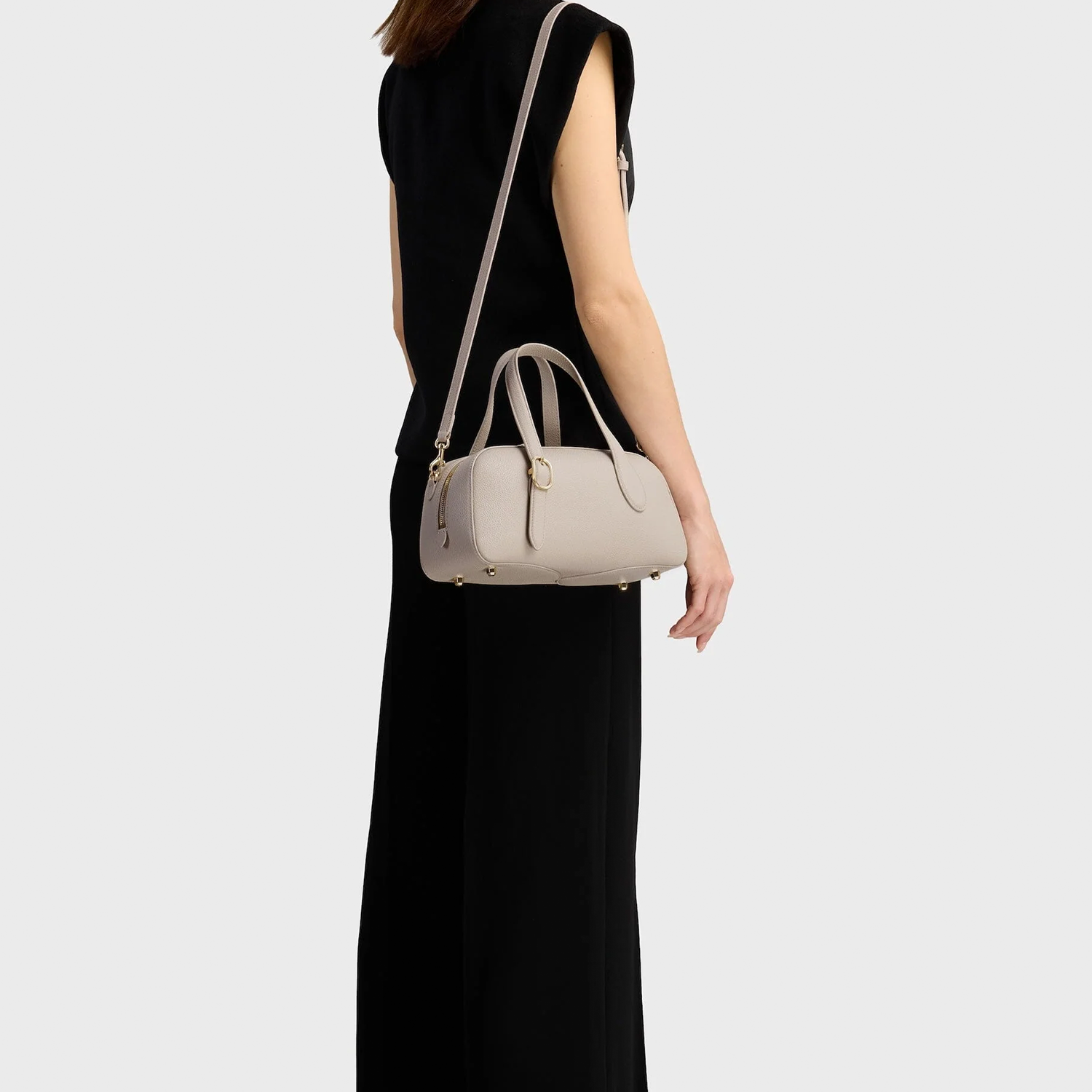 Calm Pale Ash Grey Compact Oval Barrel Carryall With Polished Golden Zipper Hardware And Base Protective Metal Studs
